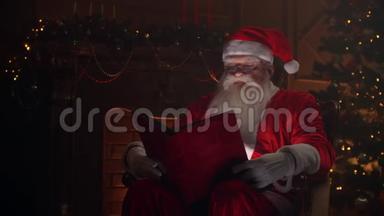 穿着圣诞老人服装的老人，坐在大气的房间里，读着一本红色封面的神奇闪亮的书-